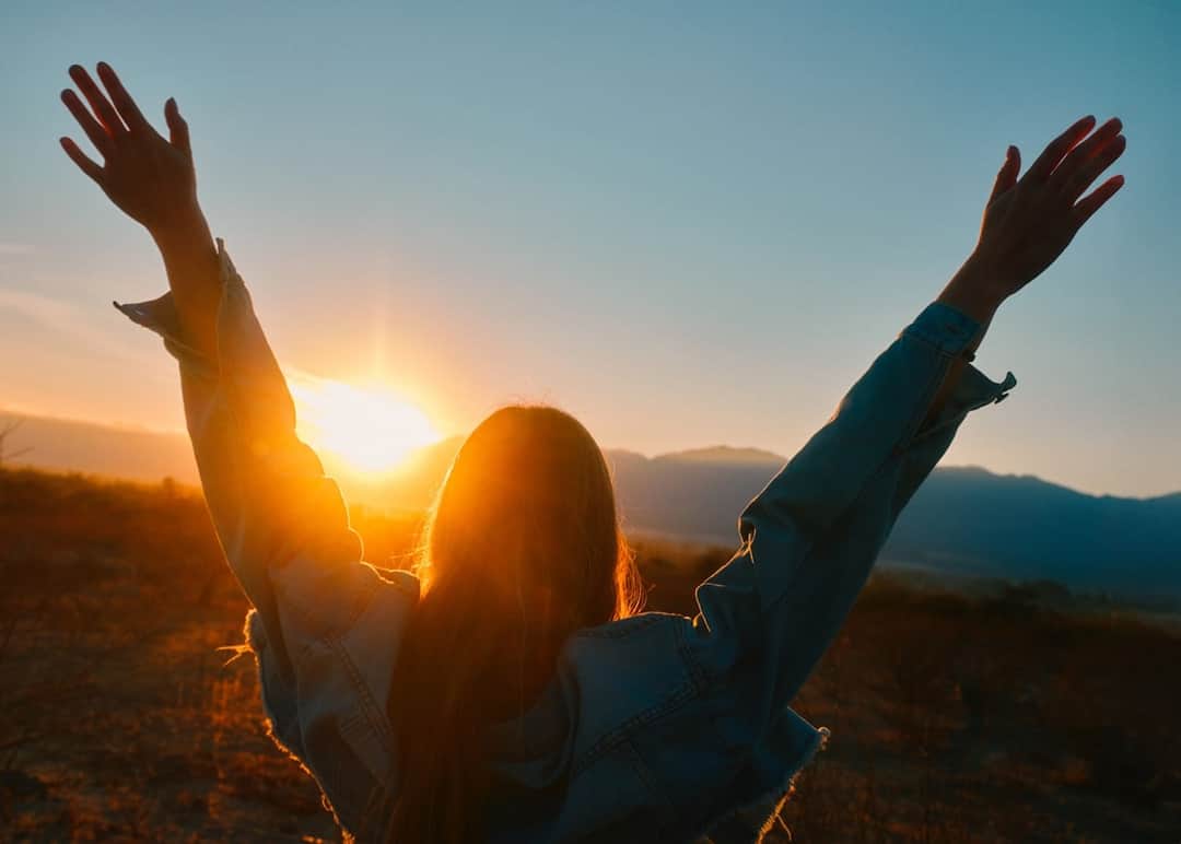 Person celebrating victory with arms raised at sunset symbolizing ecommerce success