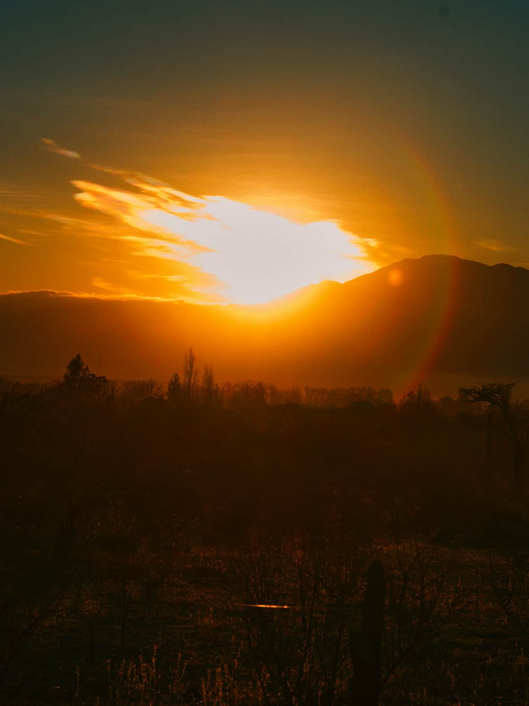 Dramatic golden sunset over silhouetted mountains illustrating temperature conditions