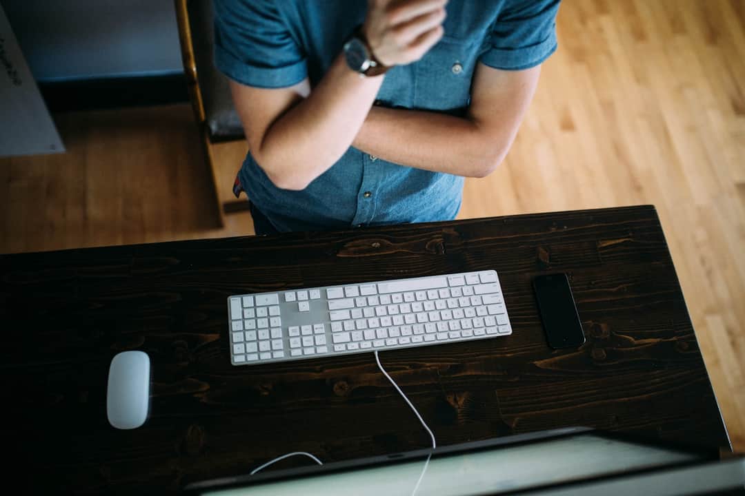 Professional at dark desk with white keyboard and mouse