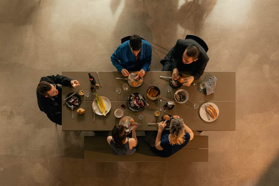 Five diners sharing a multi-course meal at a long banquet table