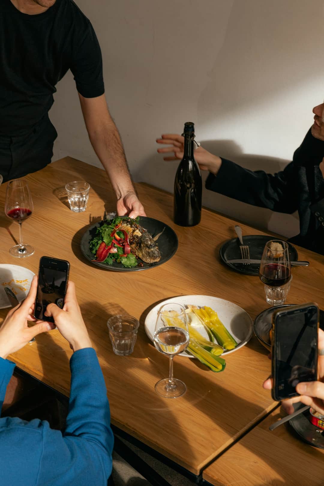 Group sharing a photo at dining banquet table with wine and food
