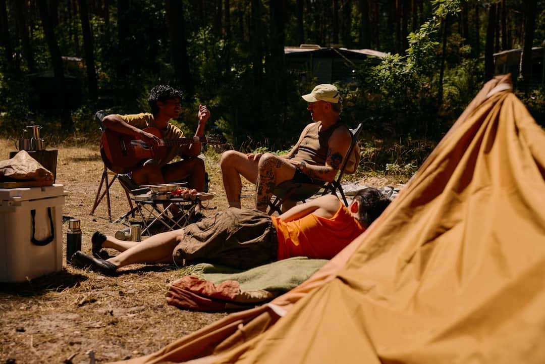 Group enjoying forest holiday at campsite with tent and chairs