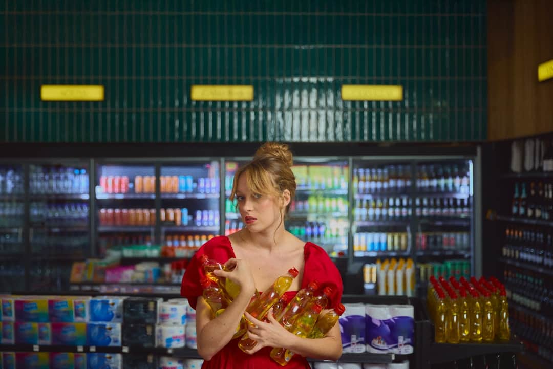 Woman holding spirits bottles in DrinkSupermarket store with refrigerated beverage shelves