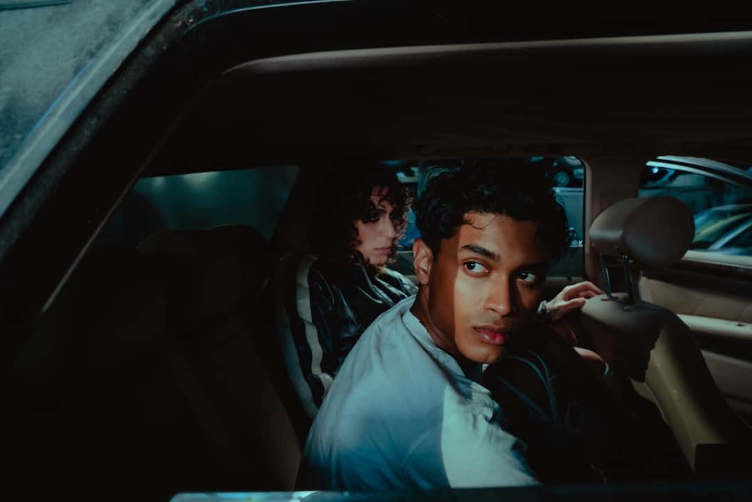 Two people in car interior lit by moody teal lighting, emphasizing design aesthetics and composition