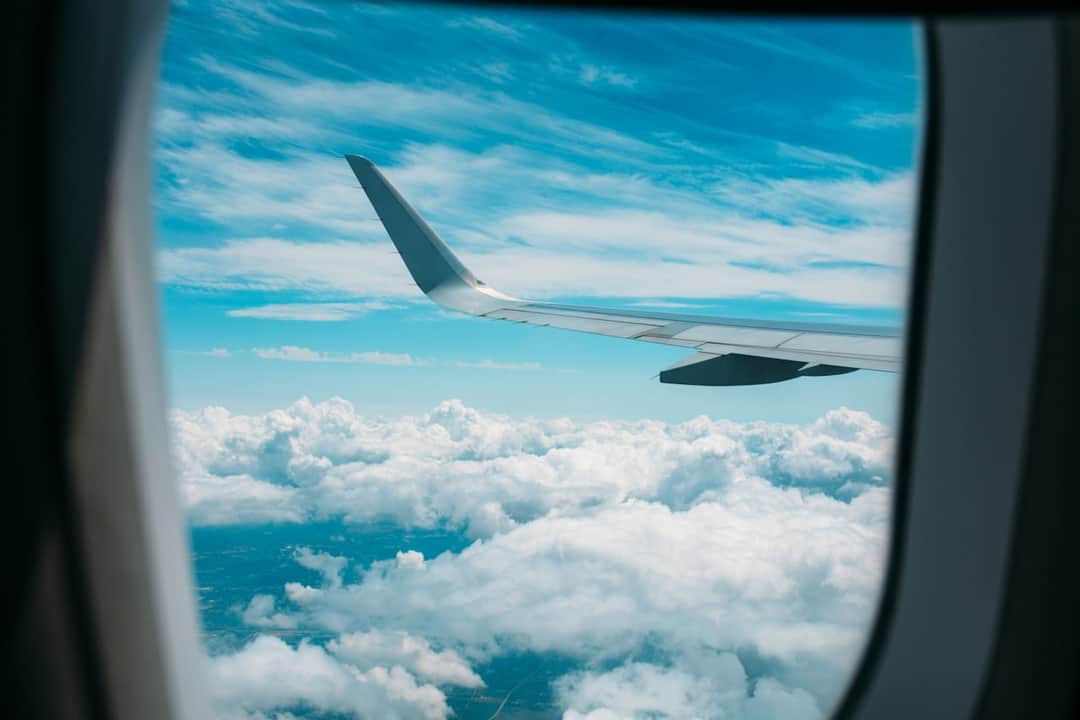 Turquoise ocean and clouds below airplane wing during travel flight