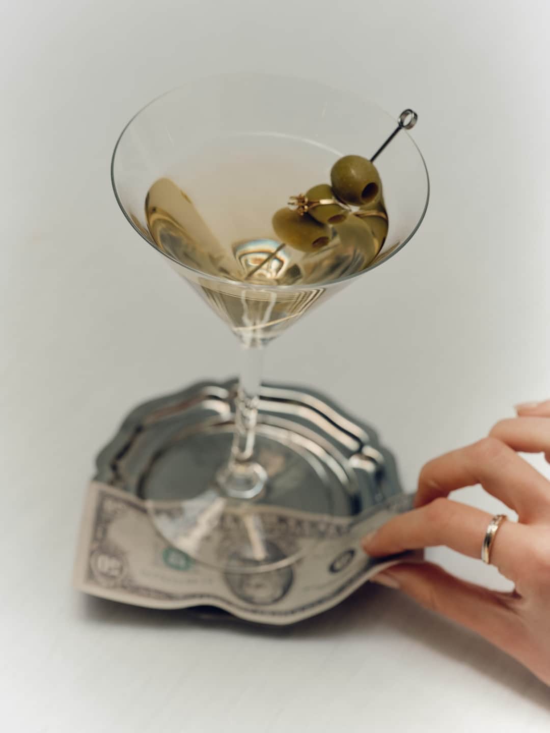 Martini cocktail with olives on currency-patterned coaster showcasing luxury alcohol marketing trends