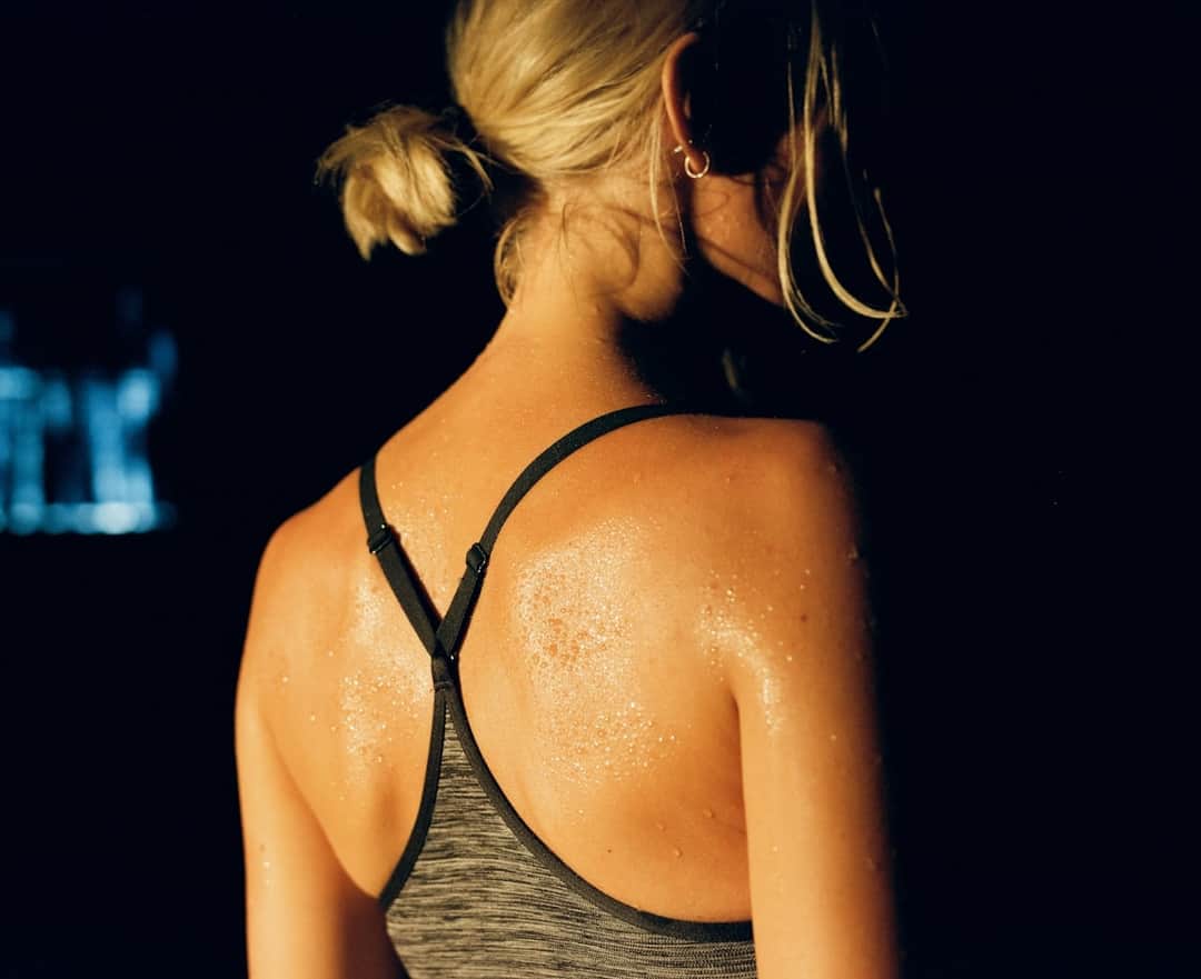 Athlete wearing sleeveless sportswear during high-intensity training, perspiring visibly