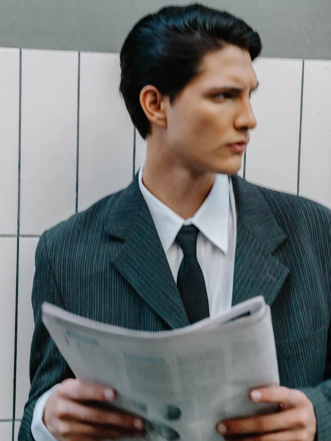 Man in pinstriped suit reading newspaper to assess trustworthy content