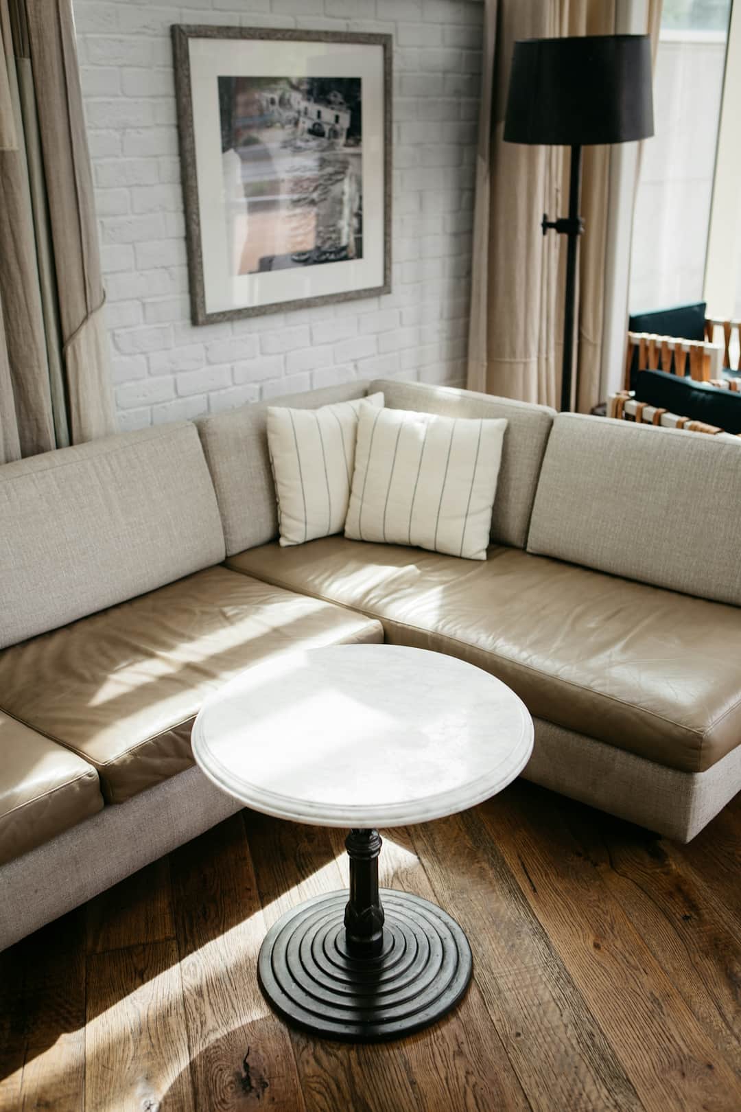 Modern beige sectional sofa with striped throw pillows and white round coffee table
