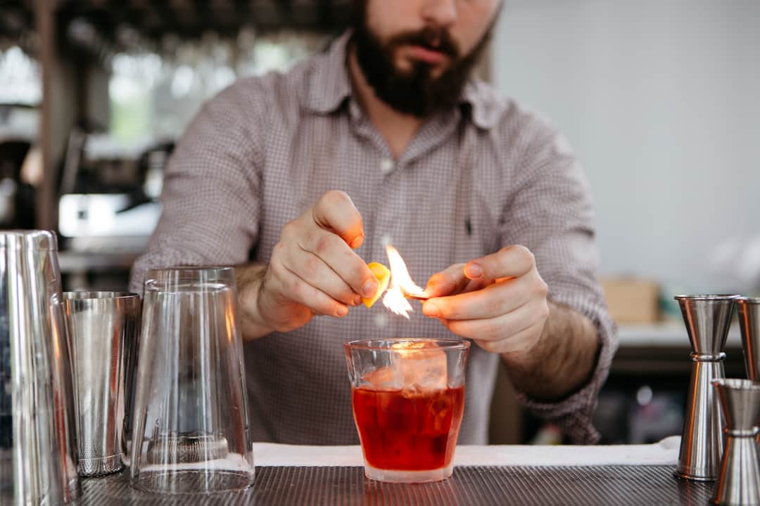 Skilled bartender garnishing a red cocktail with a vibrant citrus peel
