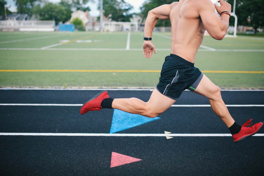 Athlete in red shoes running on track with colored geometric shapes