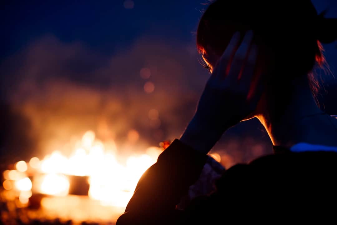 Person beside campfire evoking wildfire social moments