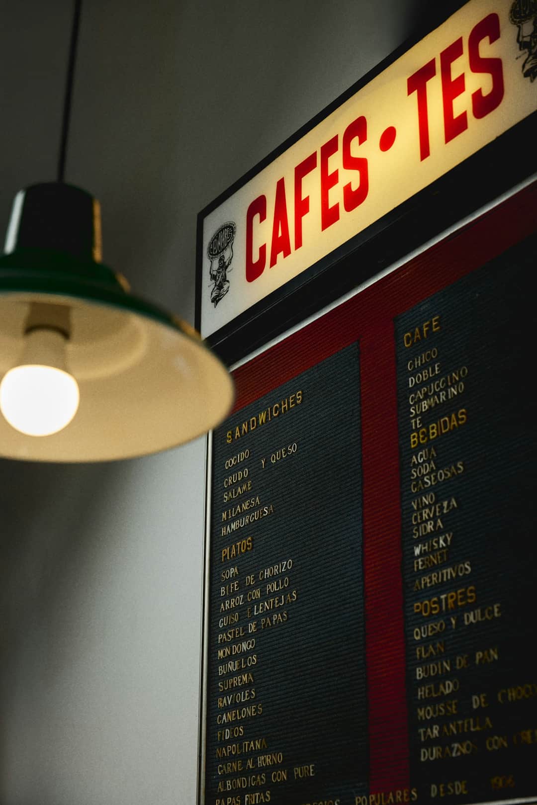 Vintage cafe storefront sign with yellow lettering and pendant lamp installation