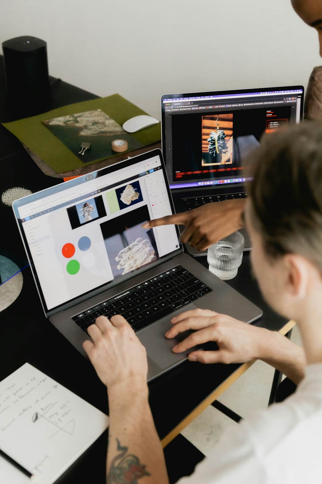 Designer working at multi-monitor workspace with color palette and image editing software