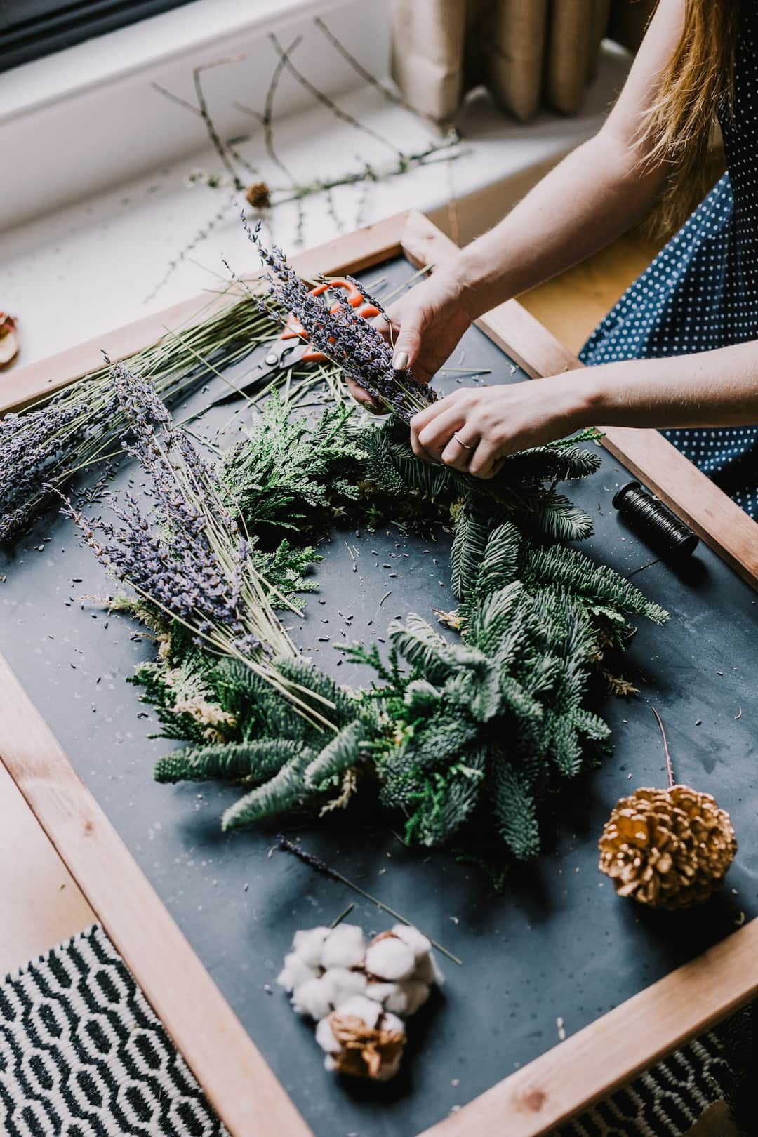 Hands styling Christmas greenery and gold ornaments for holiday decoration