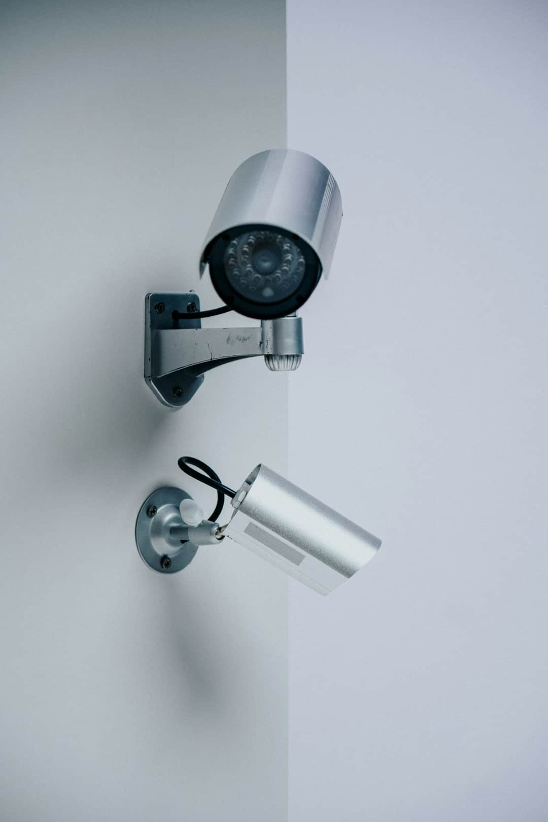 Silver dome and cylinder security cameras with infrared sensors on wall