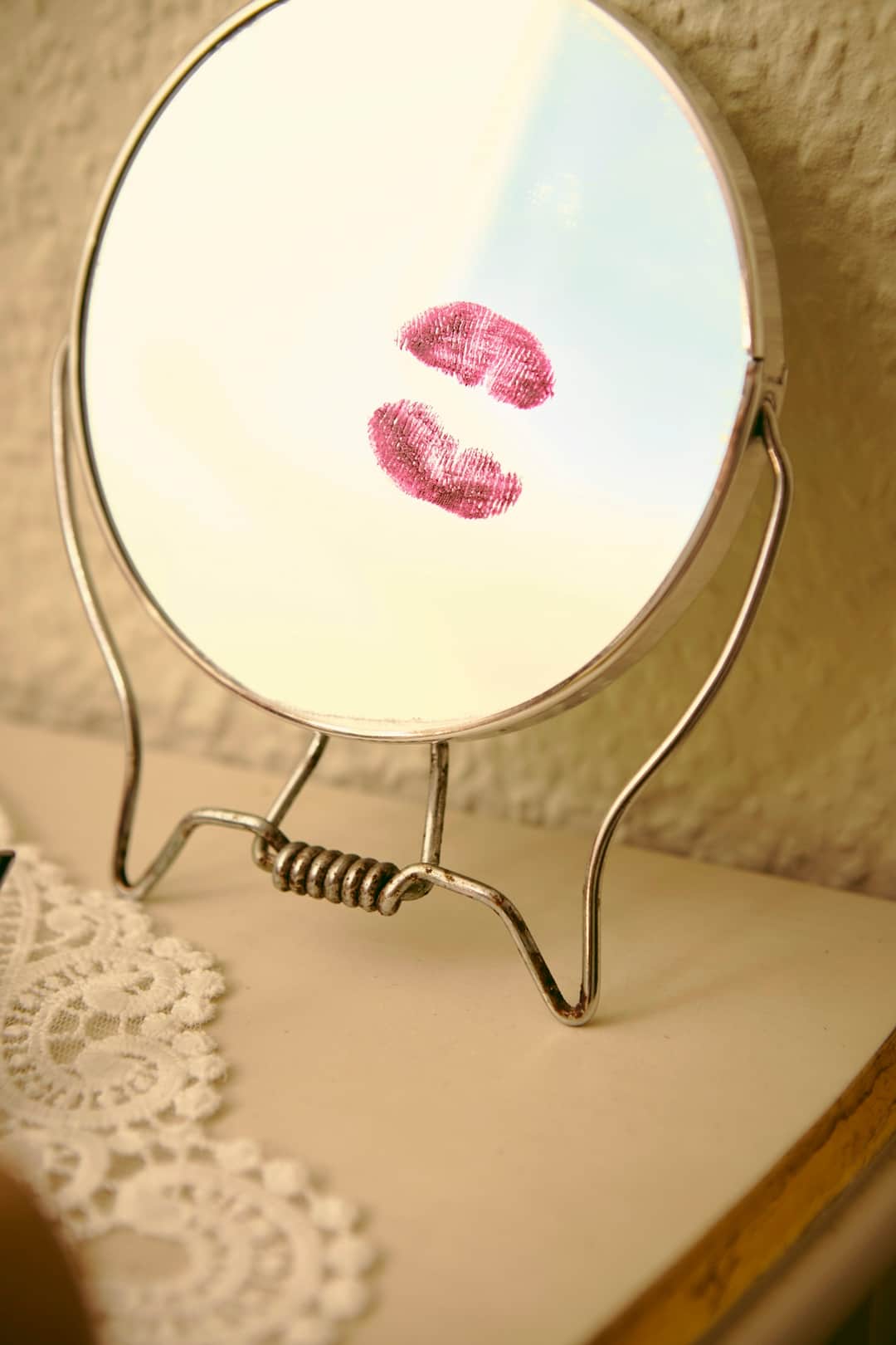 Two mauve lipstick swatches on vintage beauty mirror with metal frame