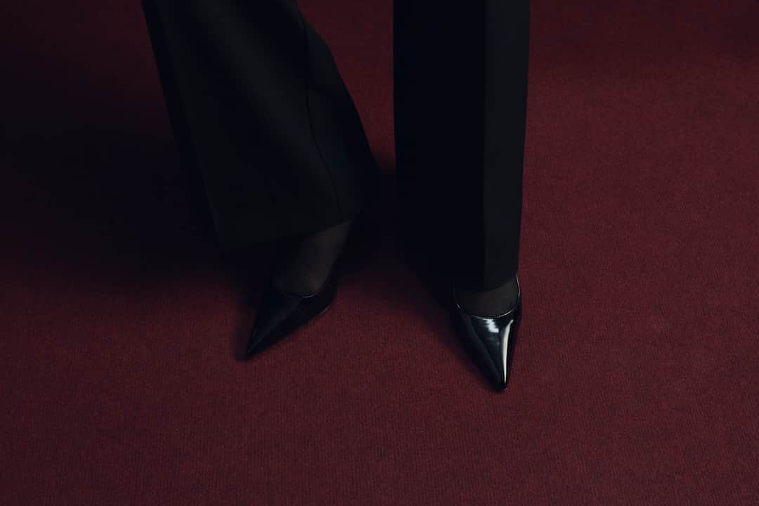 Black pointed heels on burgundy carpet flooring