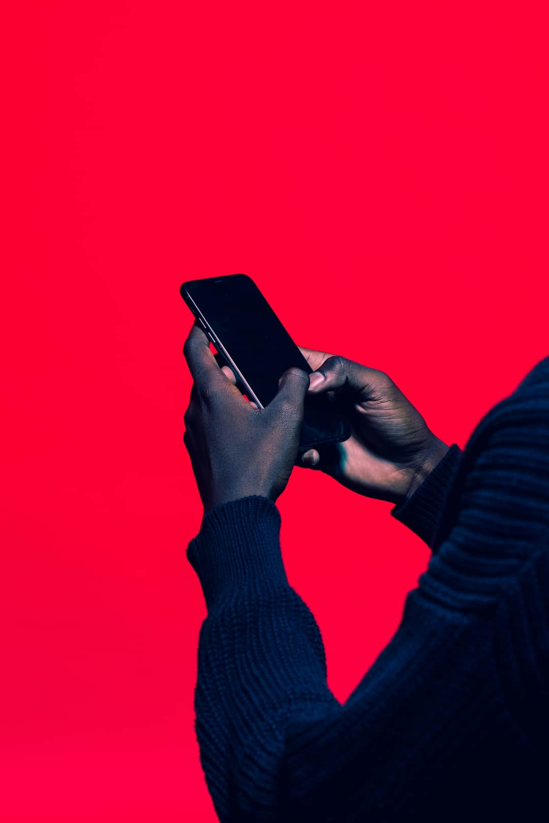 Hands holding smartphone against red background for mobile search