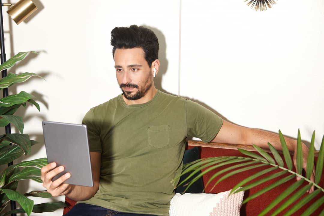 Man holding tablet displaying mobile app in modern home with plants