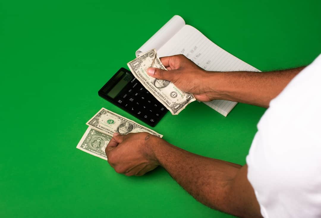 Hands holding dollar bills and calculator illustrating marketing ROI and agency accountability