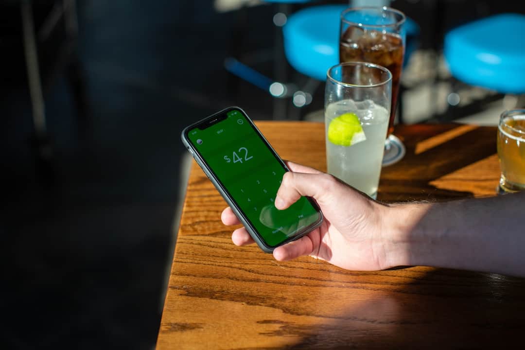 Hand holding phone displaying $42 to represent hidden costs of paid media advertising