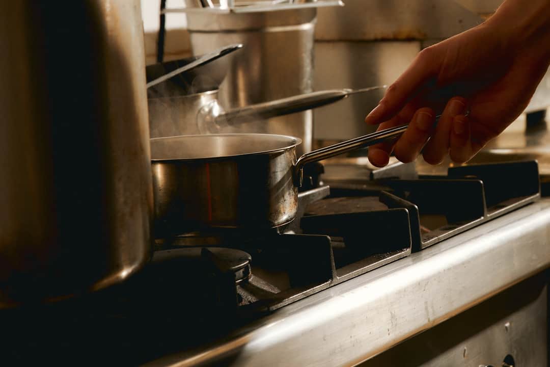 Professional chef working with premium stainless steel cookware on stovetop