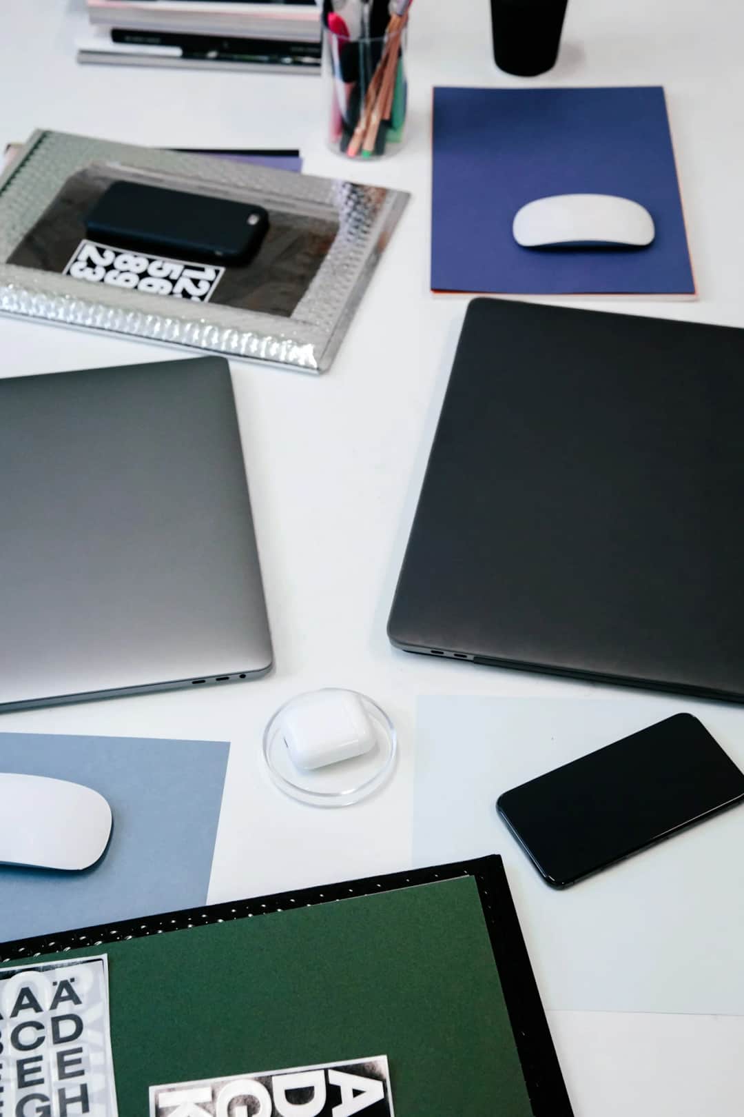 Flatlay of consumer electronics with laptops, smartphone, wireless mouse and office supplies