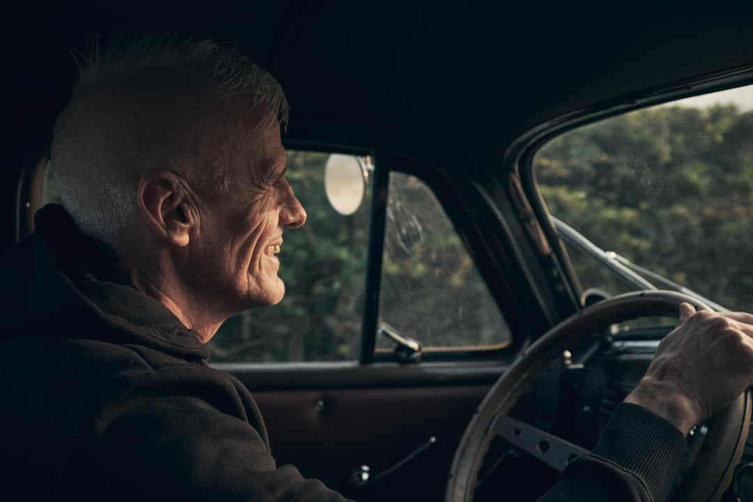 Man driving vintage car with scenic view visible through windows