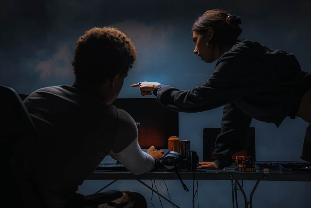 Esports player pointing at gaming station while teammate watches