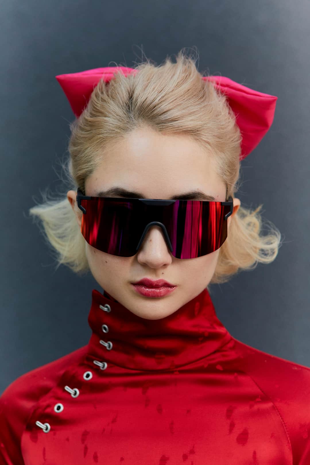 Woman in bold red metallic-striped sunglasses and matching pink cat-eye headband