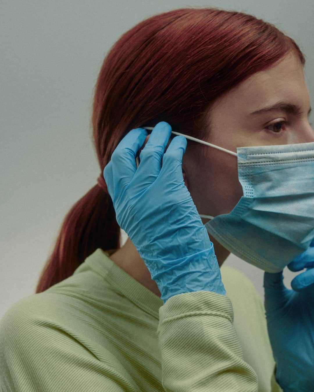 Person having face mask adjusted during COVID-19 health screening