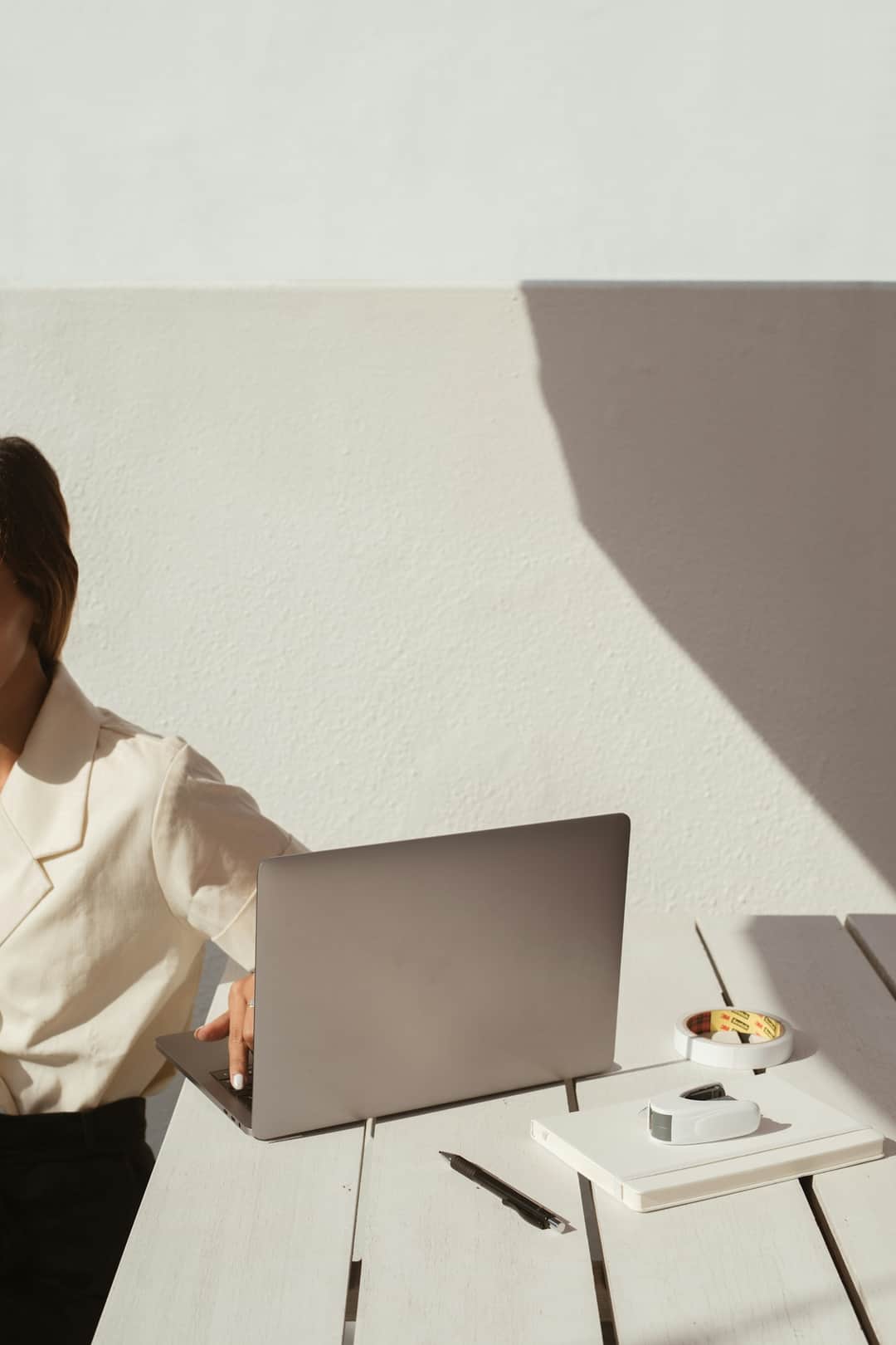 Woman writing outreach emails at laptop in clean remote studio workspace