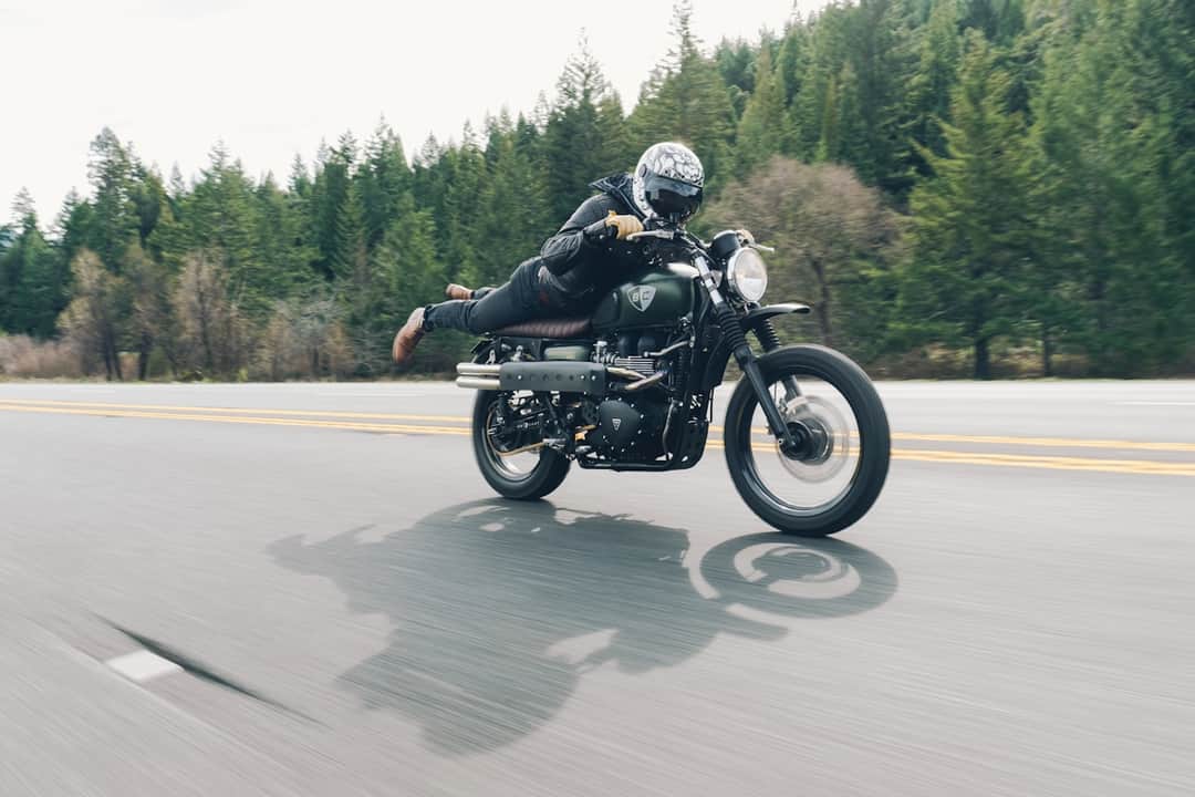 Motorcycle rider leaning into highway turn with forest backdrop
