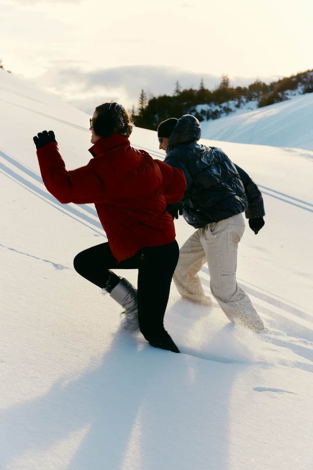 Winter hikers in outdoor clothing wading through deep snow with mountain views