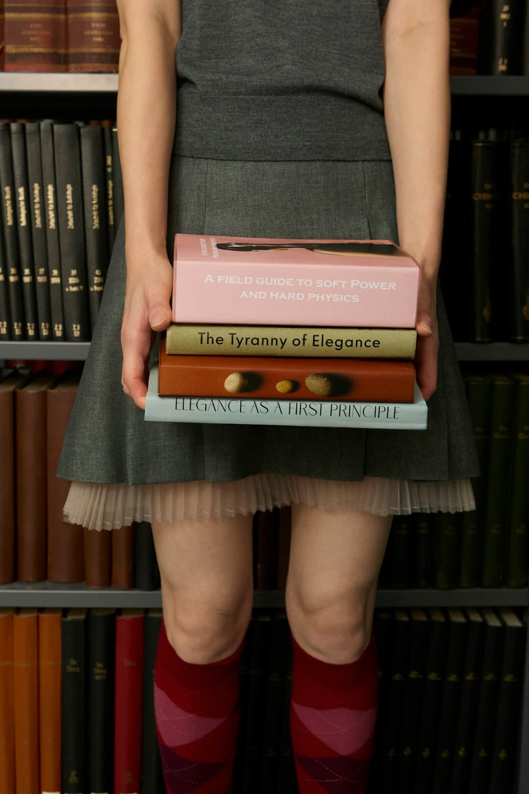 Woman holding stack of second-hand and rare books against bookshelf