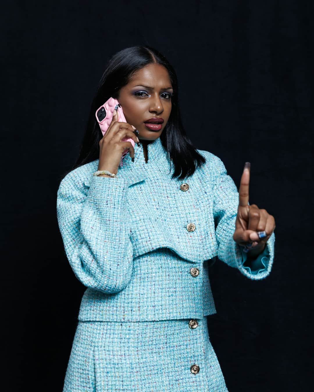 Woman in turquoise textured blazer gesturing while on phone call