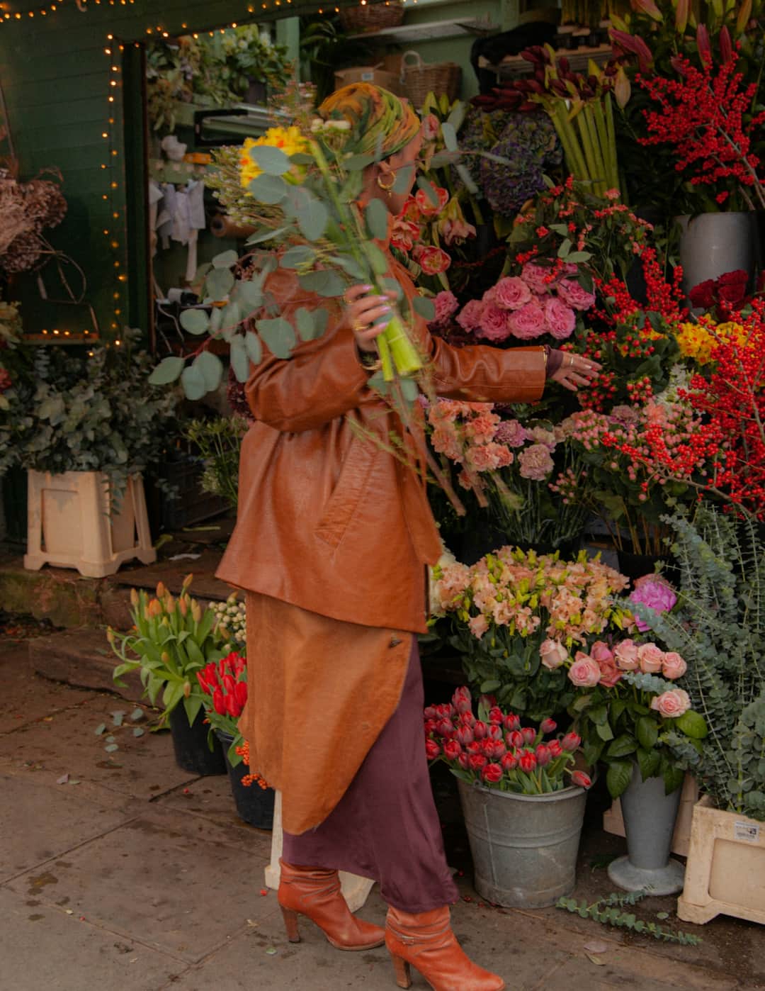 Florist holding vibrant red and pink flower arrangements in storefront display