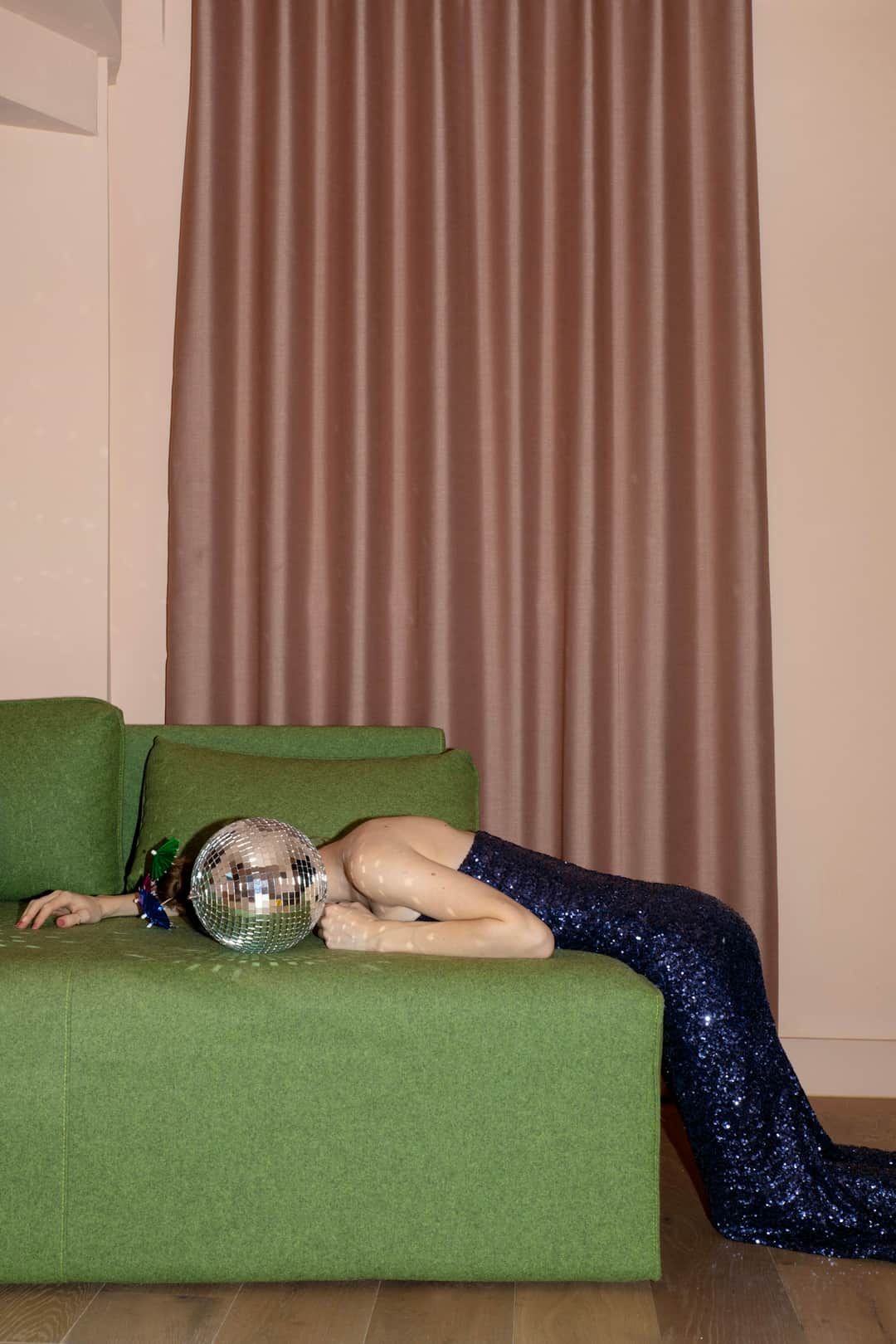 Woman lying on green couch holding disco ball, hang in there with organic search strategy