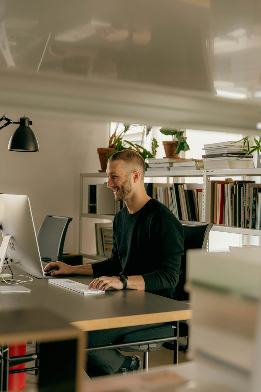 Marketing strategist at desk in contemporary studio office with laptop