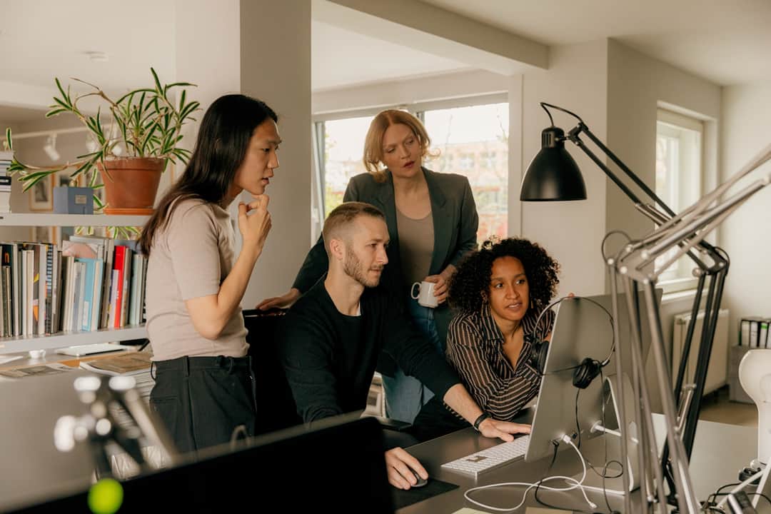 Search marketing team collaborating at modern office studio with computer workstations