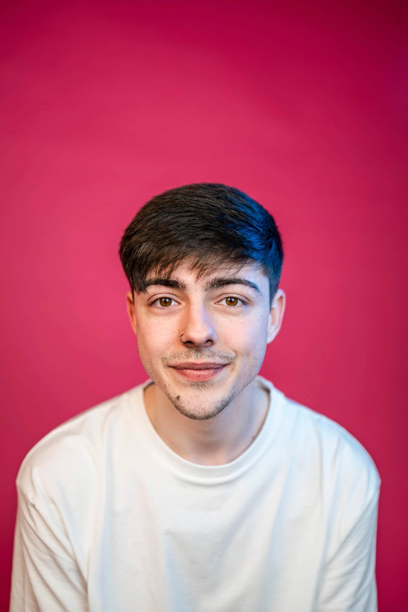 Young man wearing white shirt against magenta background