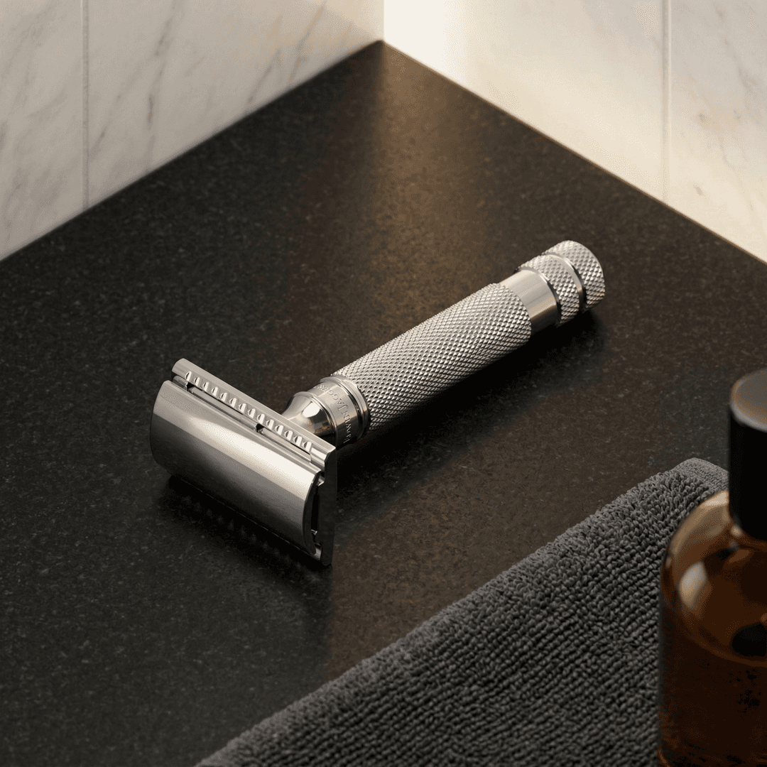 Safety razor with chrome finish and textured grip on black grooming mat