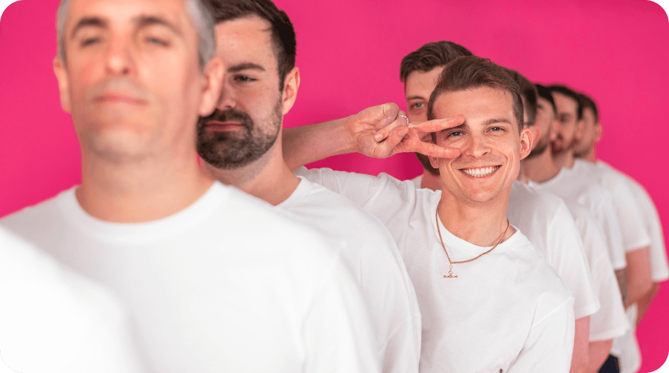 Men in white shirts lined up against a pink background, showcasing team unity at a search marketing agency.