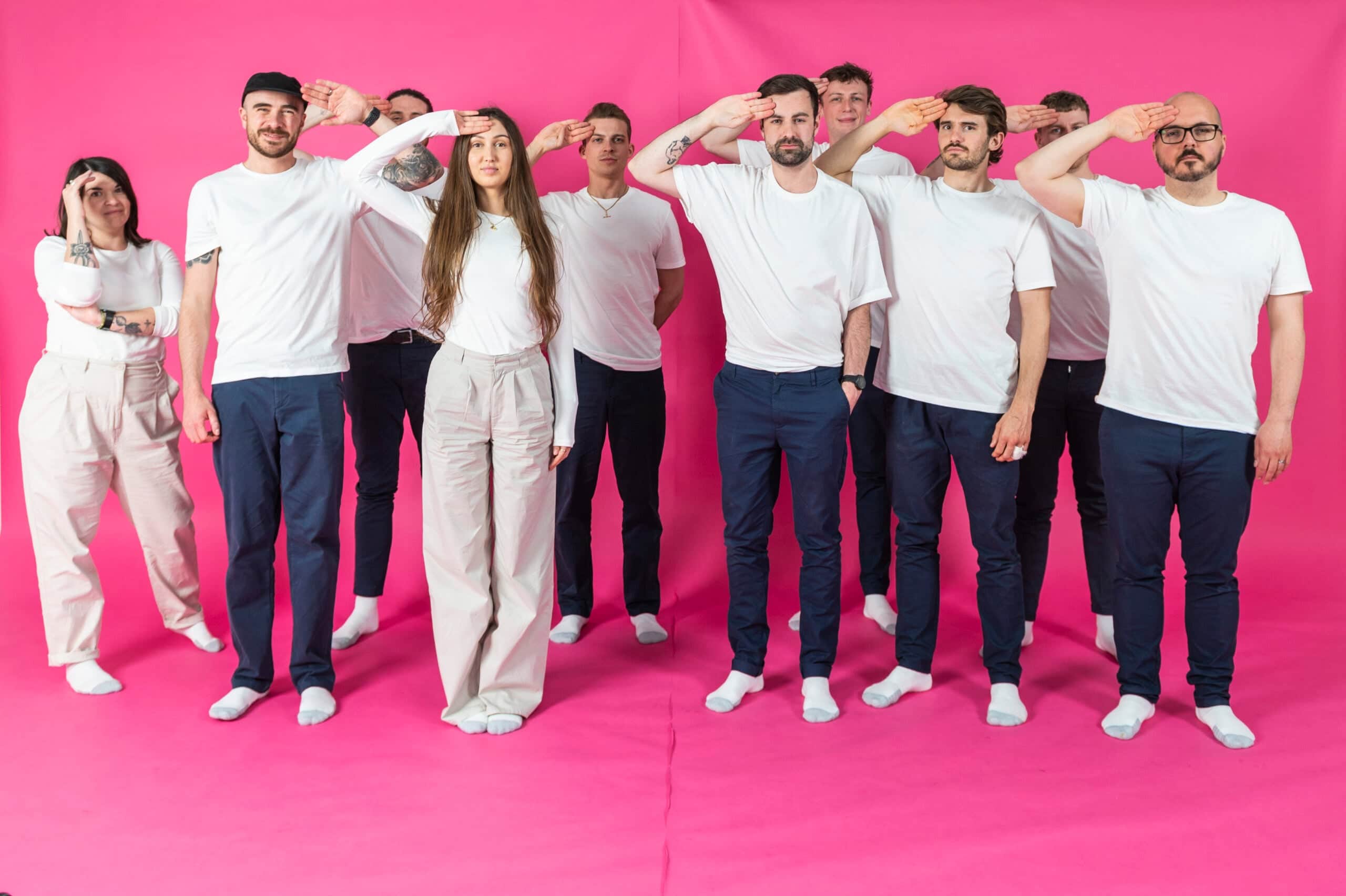 Team members posing playfully on a pink backdrop, showcasing Salience's vibrant company culture and unity.