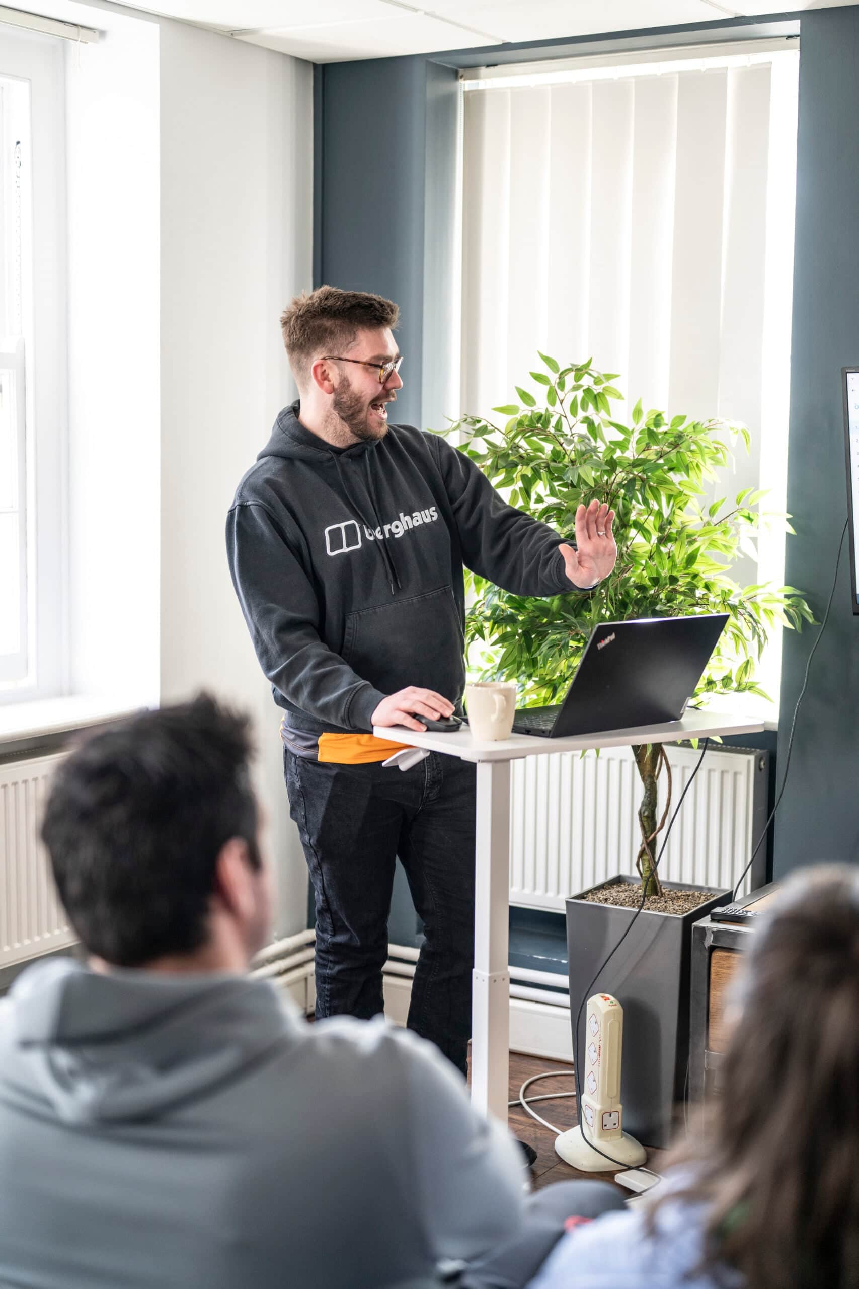 Person giving a presentation at a standing desk in an office, representing a dynamic work environment.