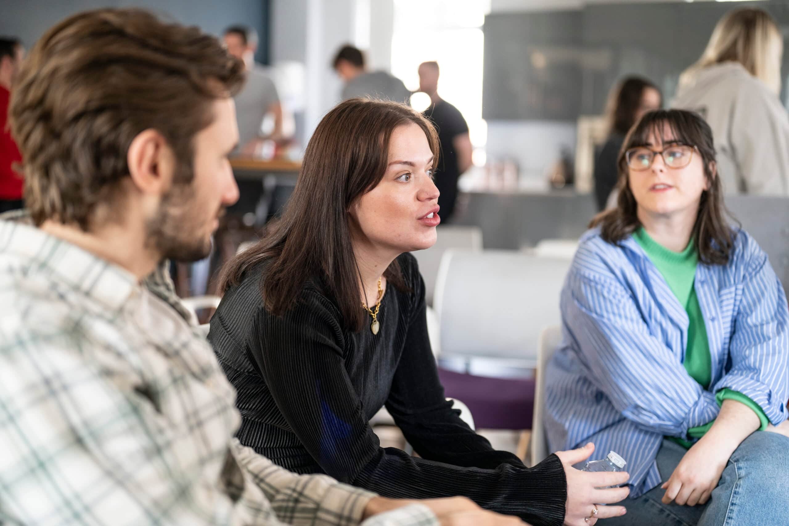 Team meeting at Salience office, three colleagues engaged in conversation, highlighting collaborative work environment.