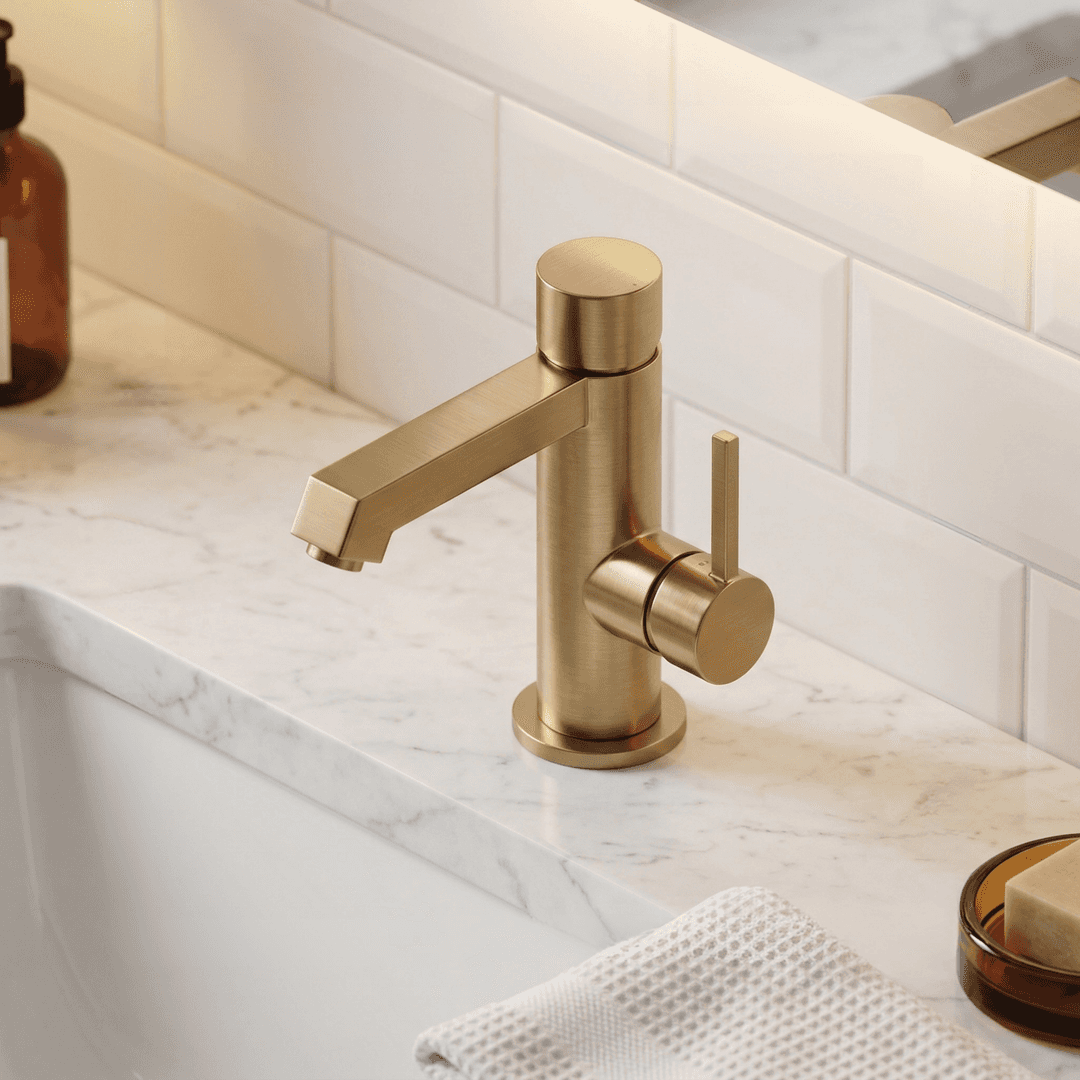Modern brass bathroom sink faucet on marble countertop with white subway tile backsplash