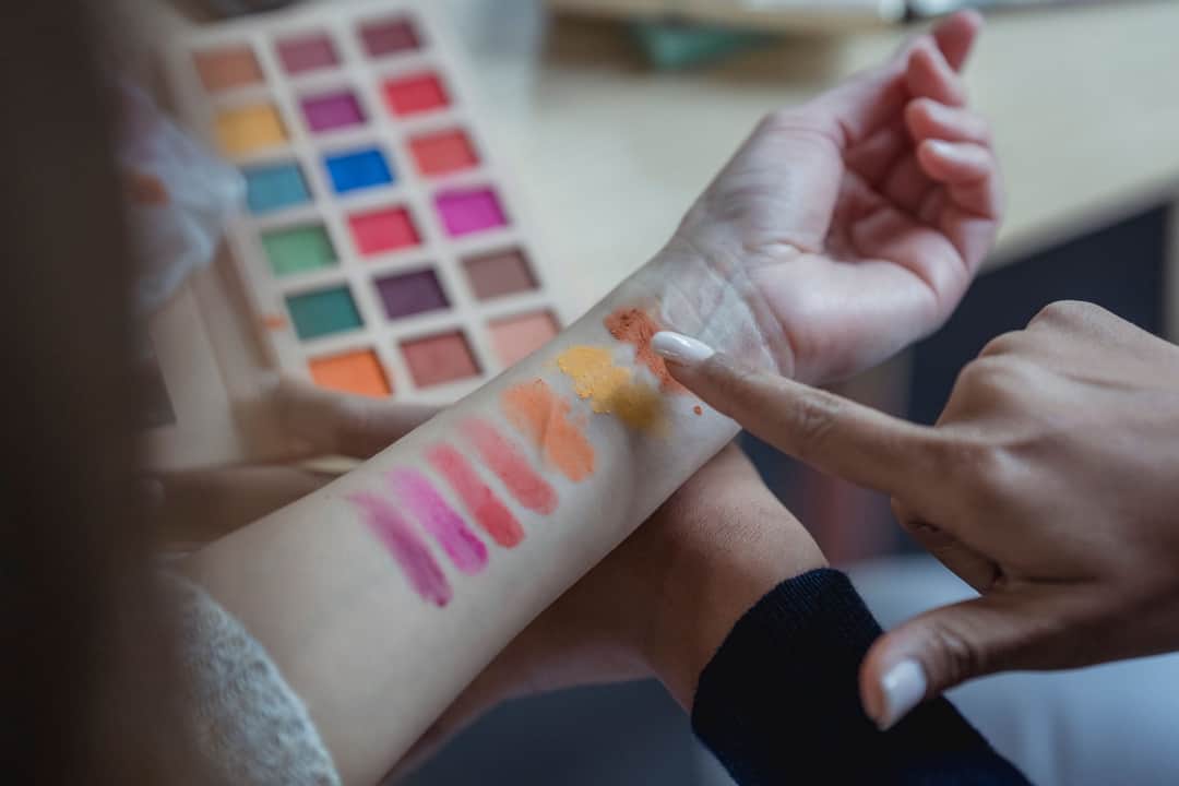 From above of crop unrecognizable young female makeup artist pointing at arm of client while applying colorful eyeshadows on wrist for testing (Photo: George Milton via Pexels)