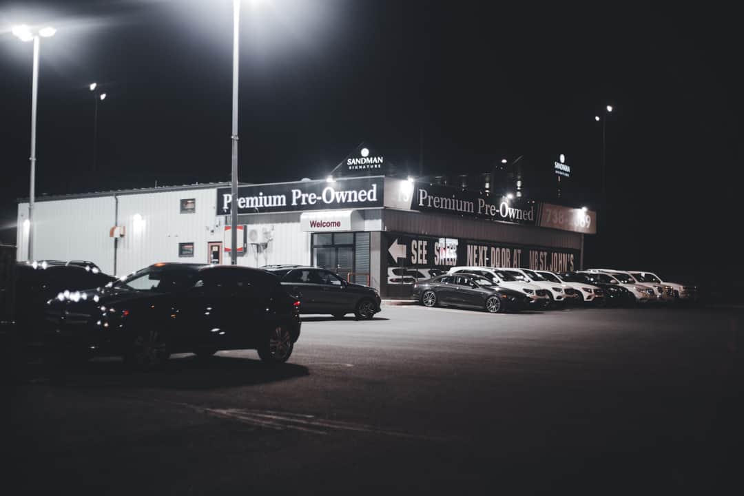 Illuminated car dealership lot showcasing premium pre-owned vehicles at night. (Photo: Erik Mclean via Pexels)